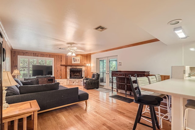 living room featuring ceiling fan, crown molding, light hardwood / wood-style floors, and french doors