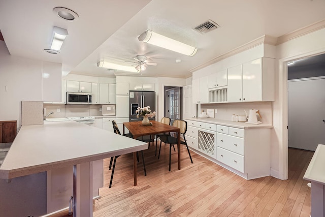 kitchen with white cabinets, appliances with stainless steel finishes, a center island, and light hardwood / wood-style floors