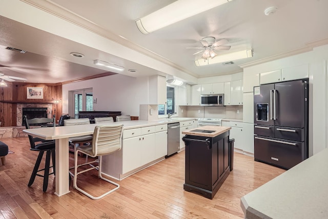 kitchen featuring white cabinetry, a center island, stainless steel appliances, and light hardwood / wood-style floors