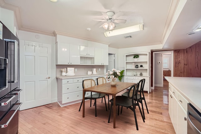 bedroom featuring light wood-type flooring, ensuite bath, ceiling fan, crown molding, and a closet