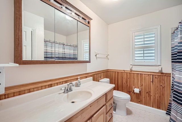 bathroom with wood walls, tile patterned flooring, vanity, and toilet