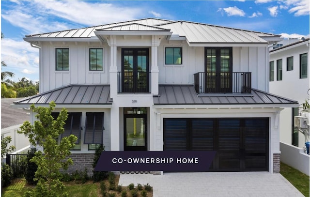 modern inspired farmhouse featuring a standing seam roof, an attached garage, metal roof, board and batten siding, and driveway