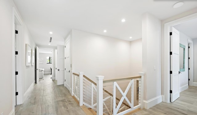 hall with baseboards, an upstairs landing, light wood-style flooring, and recessed lighting