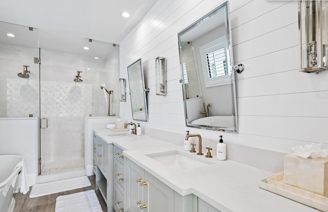 bathroom with a stall shower, double vanity, a freestanding bath, and a sink