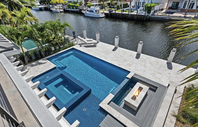 view of pool featuring a water view, a boat dock, a pool with connected hot tub, and a patio area