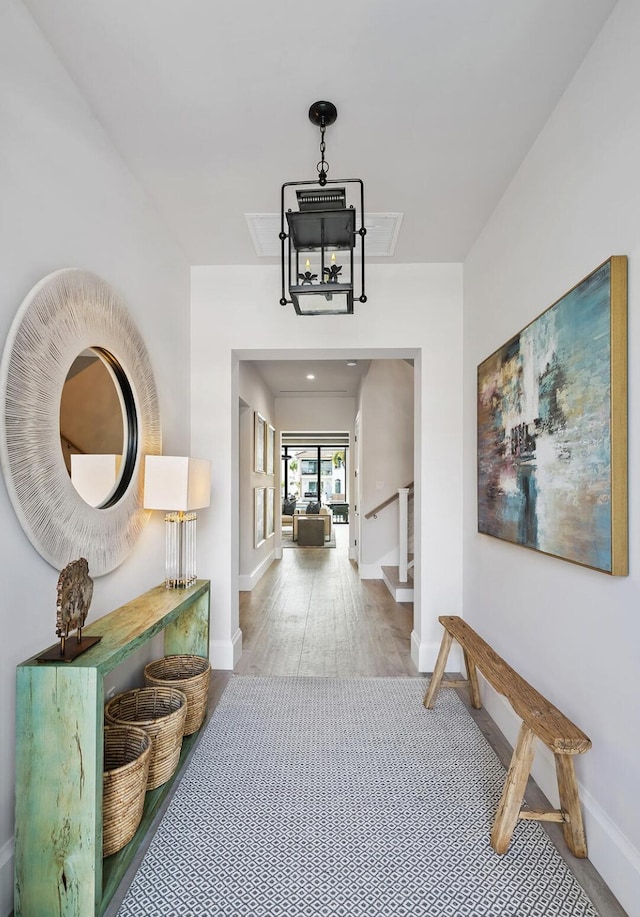 hall featuring baseboards, wood finished floors, and stairway