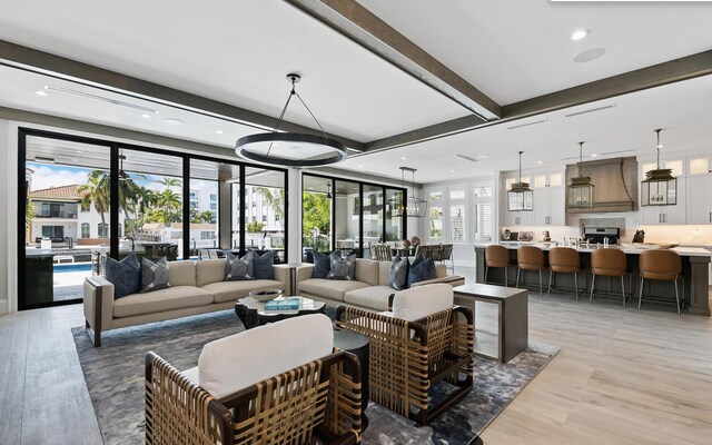 living area with light wood-style flooring, beam ceiling, and recessed lighting