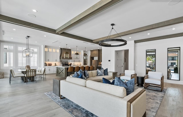 living room featuring an inviting chandelier, beamed ceiling, and plenty of natural light