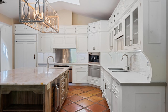 kitchen featuring white cabinets, pendant lighting, lofted ceiling, sink, and a center island with sink