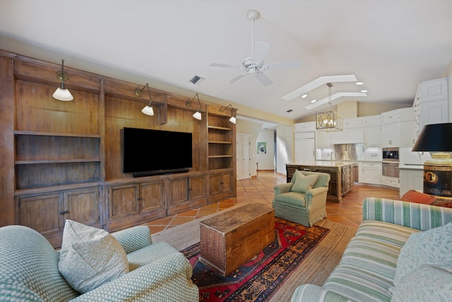 living room featuring ceiling fan with notable chandelier, lofted ceiling, and light tile patterned floors