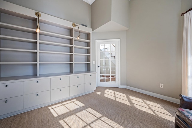 unfurnished living room with a towering ceiling and light colored carpet