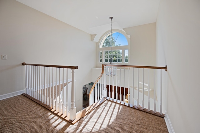 stairs featuring a chandelier and carpet