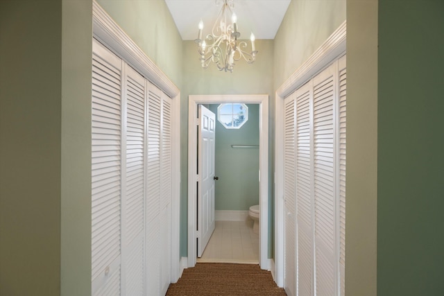 hallway with an inviting chandelier and carpet floors