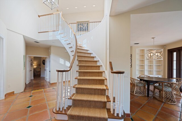 stairs with a high ceiling, a chandelier, and tile patterned floors