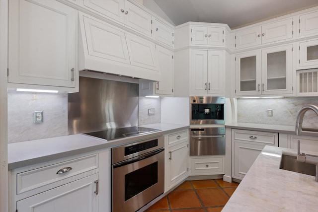 kitchen with dark tile patterned floors, black electric stovetop, white cabinets, decorative backsplash, and oven