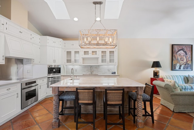 kitchen with pendant lighting, a kitchen island with sink, sink, a breakfast bar area, and stainless steel appliances