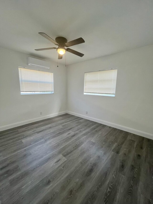 unfurnished room with dark wood-type flooring, an AC wall unit, a healthy amount of sunlight, and ceiling fan