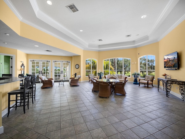 tiled living room featuring a raised ceiling, crown molding, and french doors