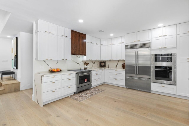 kitchen featuring backsplash, stainless steel appliances, light hardwood / wood-style flooring, and white cabinetry