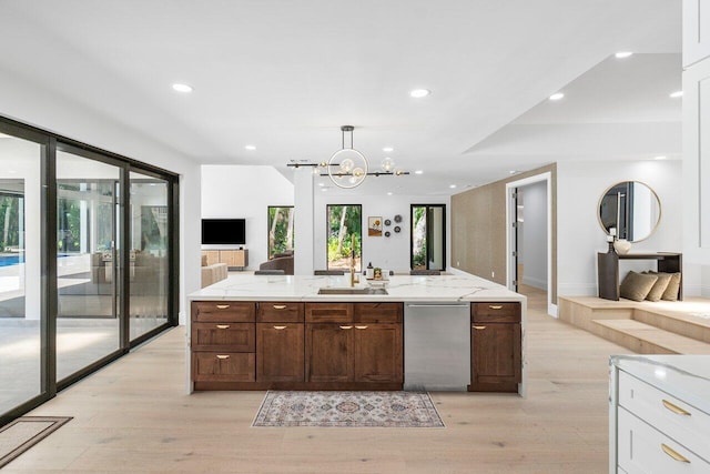 kitchen featuring dark brown cabinetry, sink, decorative light fixtures, light hardwood / wood-style flooring, and a notable chandelier