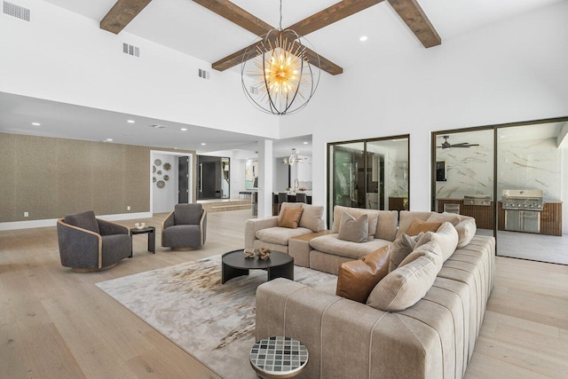 living room with beam ceiling, ceiling fan with notable chandelier, light hardwood / wood-style floors, and a high ceiling