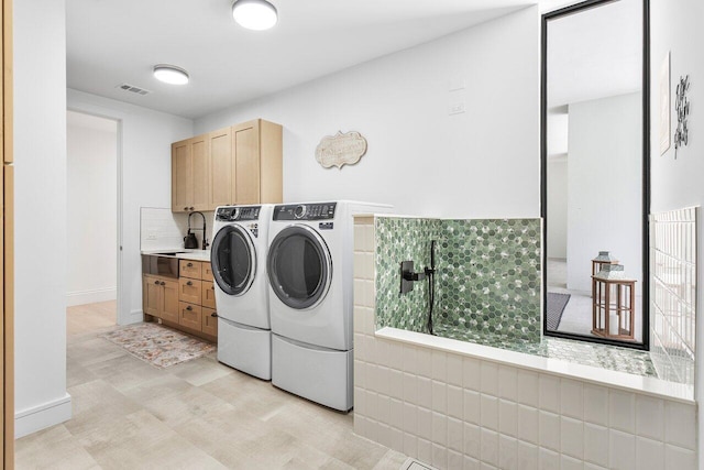 laundry room featuring washing machine and clothes dryer, sink, and cabinets