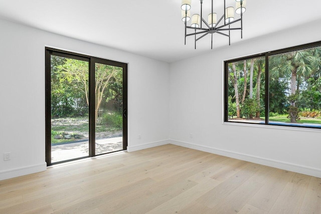 spare room with an inviting chandelier and light hardwood / wood-style flooring