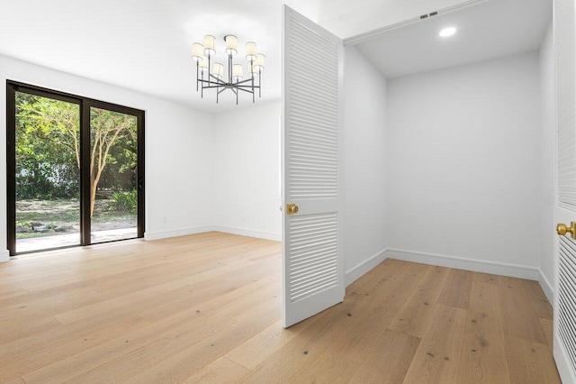 spare room featuring light wood-type flooring and a notable chandelier