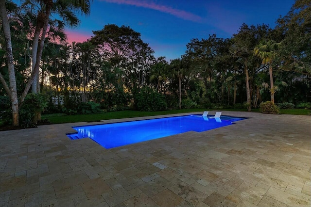 pool at dusk with a patio