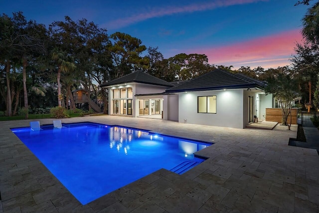 pool at dusk featuring a patio