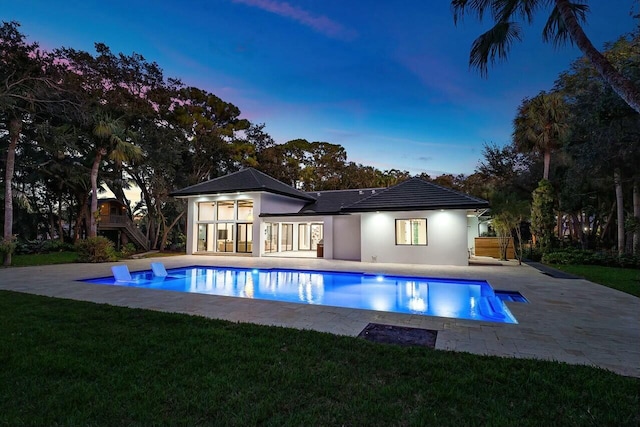 pool at dusk with a yard and a patio