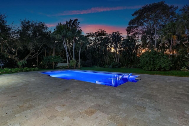 pool at dusk with a patio