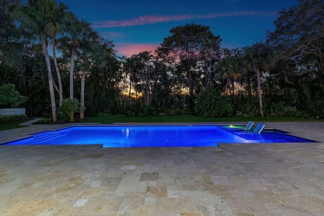 pool at dusk with a patio area