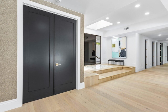 corridor with hardwood / wood-style floors and a skylight