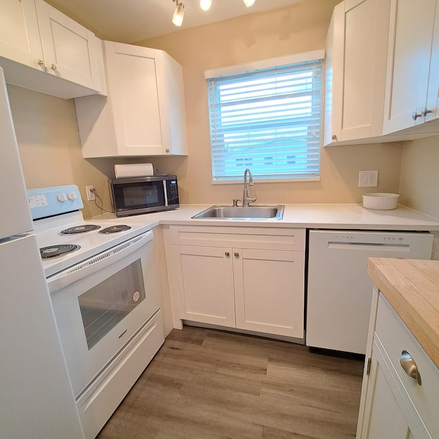 kitchen featuring white appliances, light countertops, light wood-style floors, and a sink