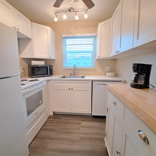 kitchen with a sink, white appliances, white cabinets, and light countertops