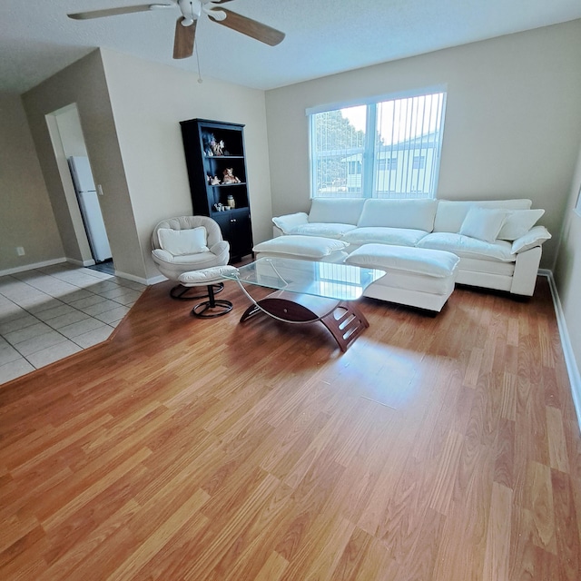 living area with baseboards, wood finished floors, and ceiling fan