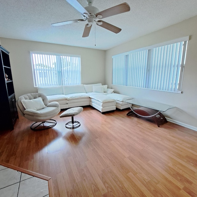 living room with a textured ceiling, wood finished floors, and a ceiling fan