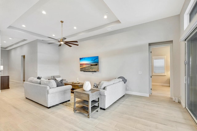 living room featuring ceiling fan, a healthy amount of sunlight, and a raised ceiling