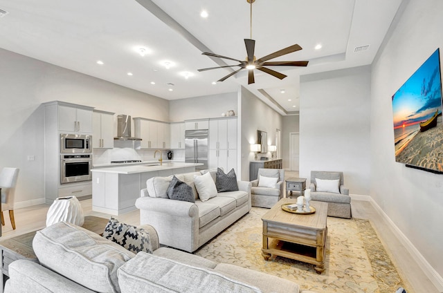 living room featuring ceiling fan, sink, and light hardwood / wood-style flooring