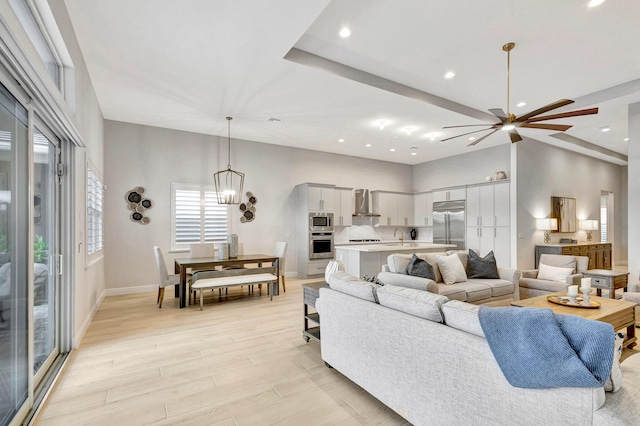 living room featuring ceiling fan with notable chandelier and sink