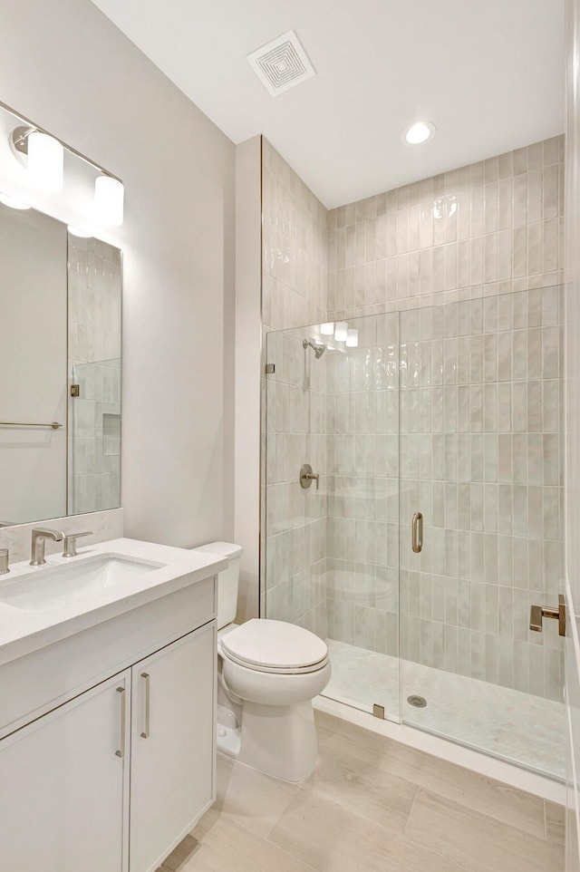 bathroom with tile patterned flooring, vanity, toilet, and a shower with shower door