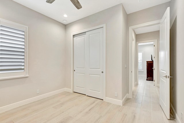 unfurnished bedroom with ceiling fan, a closet, and light hardwood / wood-style flooring