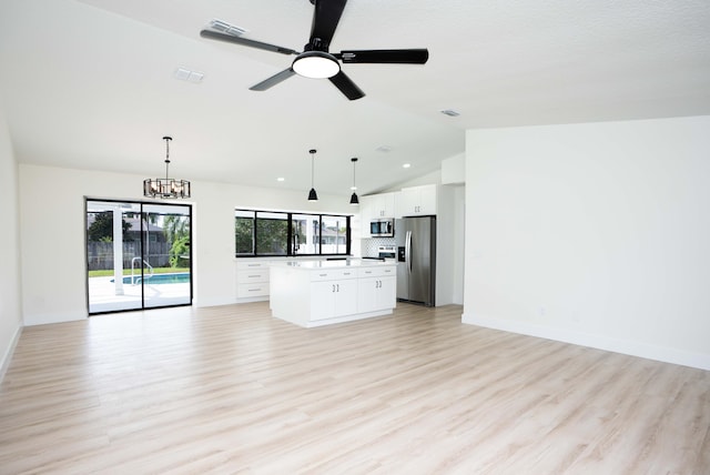 unfurnished living room featuring a textured ceiling, vaulted ceiling, ceiling fan with notable chandelier, and light wood-type flooring