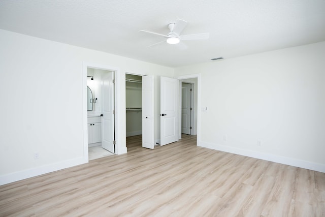 unfurnished bedroom with ceiling fan, a spacious closet, connected bathroom, light hardwood / wood-style floors, and a closet