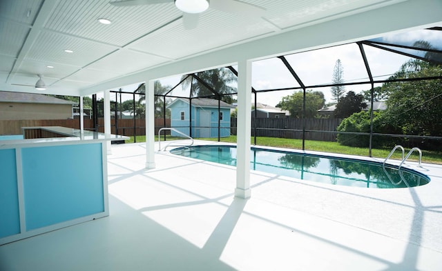 view of swimming pool with a shed, a patio area, and glass enclosure