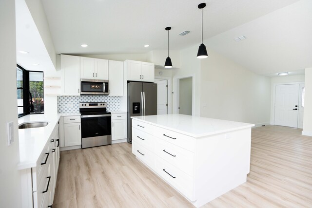 kitchen with stainless steel appliances, lofted ceiling, pendant lighting, and white cabinets