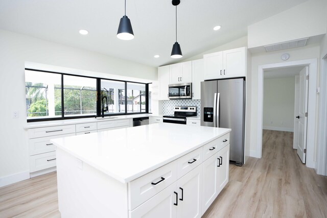 kitchen featuring appliances with stainless steel finishes, sink, a center island, white cabinetry, and pendant lighting