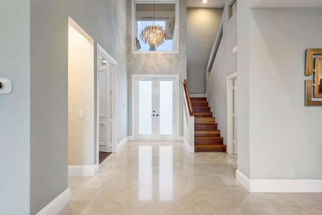 foyer entrance with french doors, an inviting chandelier, and a high ceiling