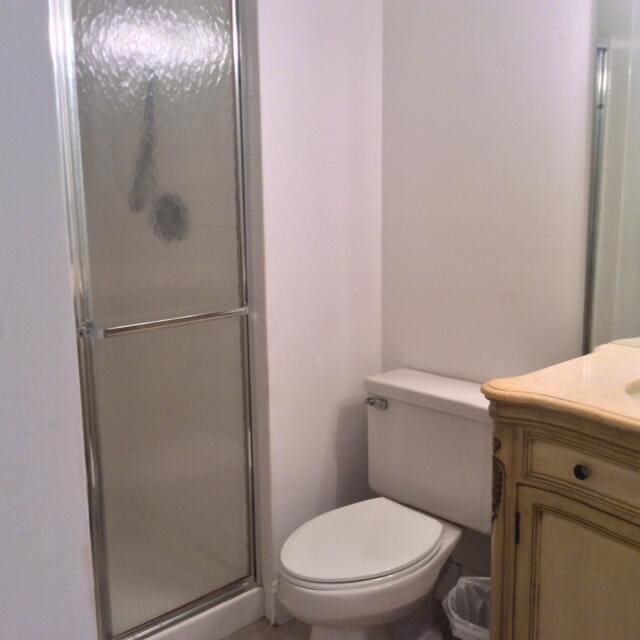 bathroom featuring vanity, an enclosed shower, and toilet